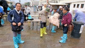 ベネチアの街で靴カバーを装着する人々