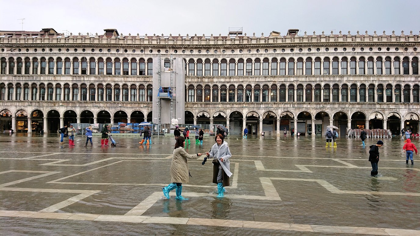 ベネチアのサンマルコ広場で冠水している広場で記念撮影する観光客