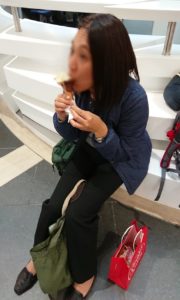 ローマ空港内の案内所前でチョコレートを食べて油断する添乗員さん