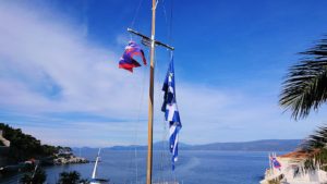 エーゲ海のイドラ島の高台になびくギリシャ国旗を見る