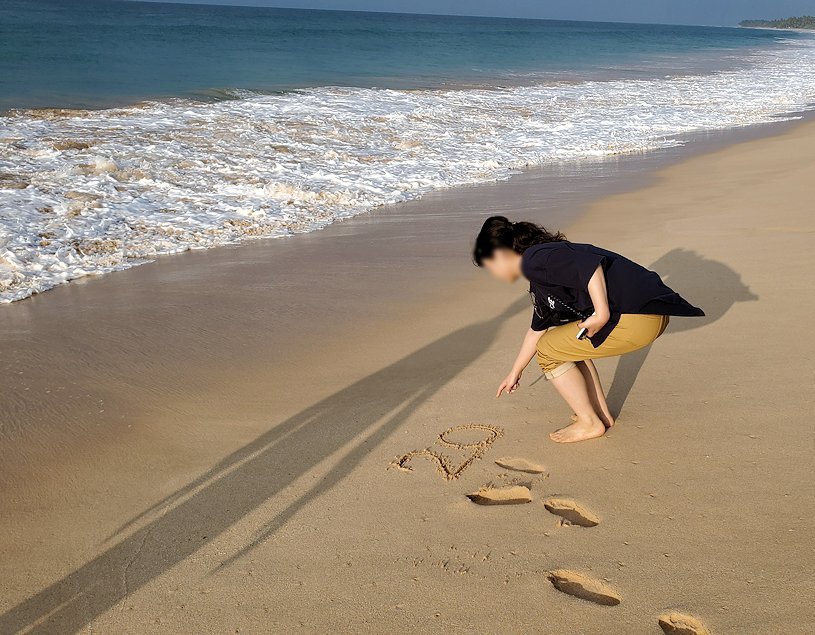 「ロング・ビーチ・リゾートホテル」のビーチで砂浜に文字を書くお姉さん