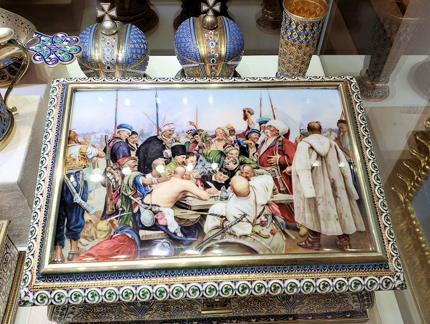 イリヤー・レーピン(Ilya Repin)が1880年から約10年掛かって描いた『トルコのスルタンへ手紙を書くザポロージェ・コサック』(Reply of the Zaporozhian Cossacks)の絵が、蓋に描かれていた
