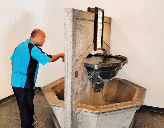北九州市門司港にある、門司港駅の構内にある歴史ある手洗い場で顔を洗うオジサン
